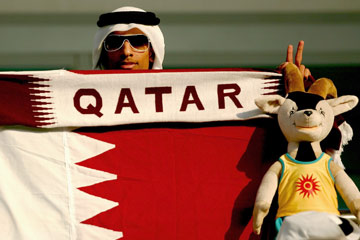 A Qatar football supporter with national flag and Orry toy © Getty Images