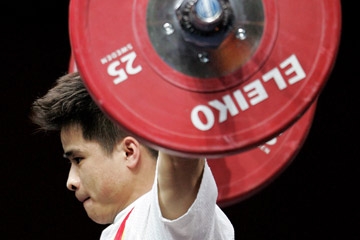 A weightlifter holds the bar above his head on an attempt © Getty Images