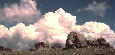 A photo of clouds behind a rock formation