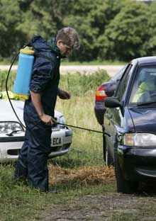 A worker sprays disinfectant on a car outside a farm in Normandy, England on Tuesday.