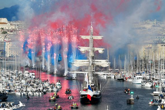 Fireworks go off as the French 19th-century three-masted barque Belem (C) arrives at the Vieux-Port (Old Port) during the Olympic Flame arrival ceremony, ahead of the Paris 2024 Olympic and Paralympic Games, in Marseille, southeastern France, on May 8